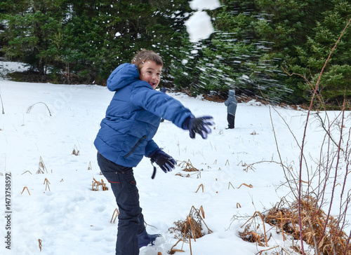 Boy in blue warm jacket having fun with snowballs in beautiful winter place