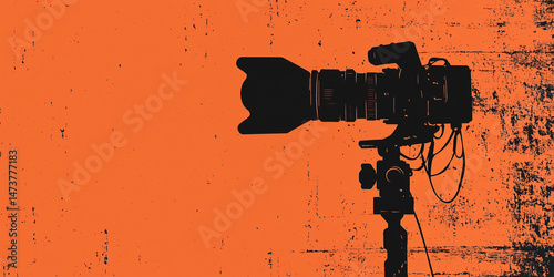 Silhouette of a digital video camera mounted on a tripod against a vibrant orange backdrop - film recording concept