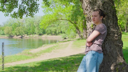 A teenage girl is relaxing in a beautiful spring forest. The landscape is filled with green leaves.
