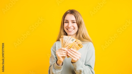 Canvastavla Happy woman holding euro banknotes on yellow background
