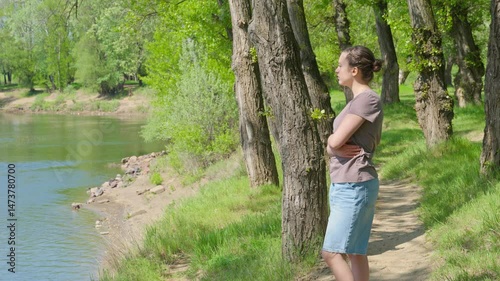 A teenage girl is relaxing in a beautiful spring forest. The landscape is filled with green leaves.

