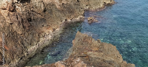 Waves crash against towering rocks on a rugged seaside, where the power of nature meets raw coastal beauty