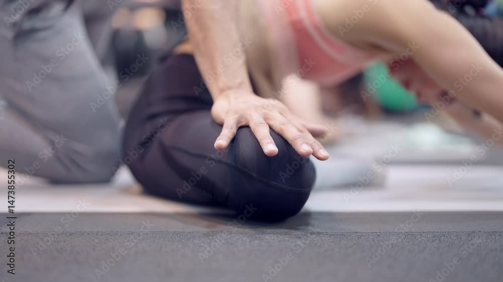 A man is helping a woman with her yoga pose. The woman is kneeling on the ground. The man is on her left side A man is helping a woman with her yoga pose. The woman is kneeling on the ground. The man is on her left side