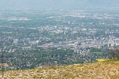 Vue panoramique spectaculaire du bassin genevois depuis le Salève, révélant la ville de Genève, le lac Léman et les montagnes environnantes sous une lumière naturelle et dégagée.