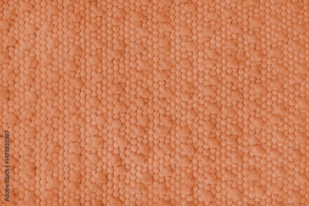 Fototapeta premium Texture of orange carpet fabric with large coarse textured weaving. Surface, structure of upholstery or rug material, cloth background close up, macro.