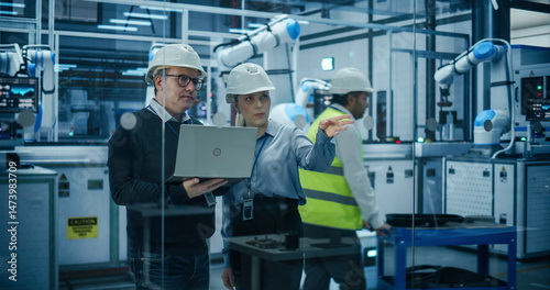 Wallpaper Mural Female and Male Industrial Engineers Using Laptop Computer, Having a Conversation at a Modern Tech Electronics Factory with Automated Robot Arms Working with the Help of AI Software Torontodigital.ca