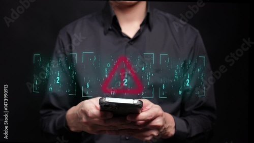 A person in a black shirt is typing on a mobile phone with a futuristic screen displaying a red exclamation symbol, indicating a cyber threat or hacking attempt.