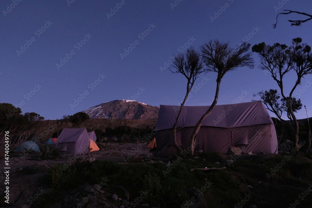 Mweka Camp on Kilimanjaro, Tanzania with tents on camp and Kilimanjaro peak in background.