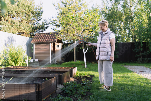 woman is watering plants with garden hose