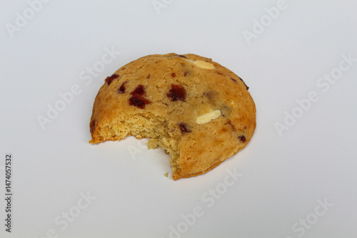 A bitten white choco soft cookie with almond and berry cuts, isolated on white background