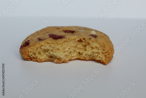 A bitten white choco soft cookie with almond and berry cuts, isolated on white background