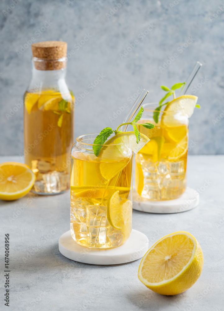 Fototapeta premium Two glasses and bottle with iced drink with lemon and mint on a light background
