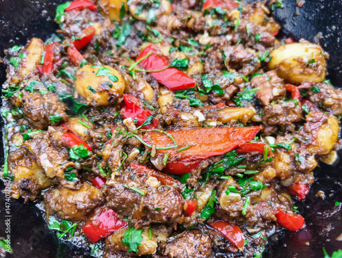 Spicy beef stir-fry with peppers and potatoes prepared outdoors during a sunny day
