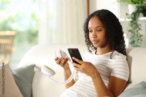 Valokuva Black woman pairing wireless headphone with smart phone