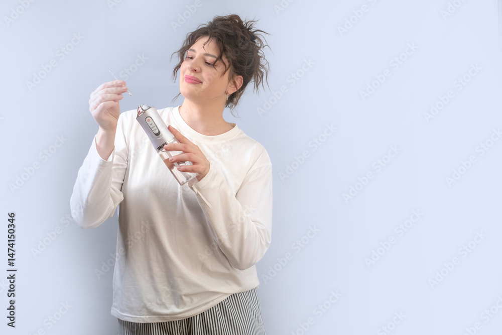 Teeth cleaning with a water flosser at home. Woman taking care of her dental health following dentist's recommendation. Teeth cleaning with a water flosser at home. Woman taking care of her dental health following dentist's recommendation.