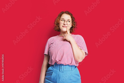  A thoughtful woman in a red t-shirt isolated on a clear background with copy space.