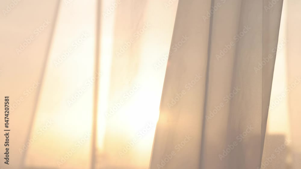 Light breezy sheer curtain blowing in the wind with sunset behind it