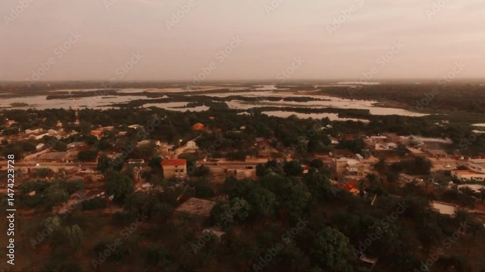 Lever du jour à Cap Skirring depuis les airs, révélant un village paisible niché entre végétation tropicale et bolongs lointains, dans une atmosphère douce et lumineuse typique de Casamance