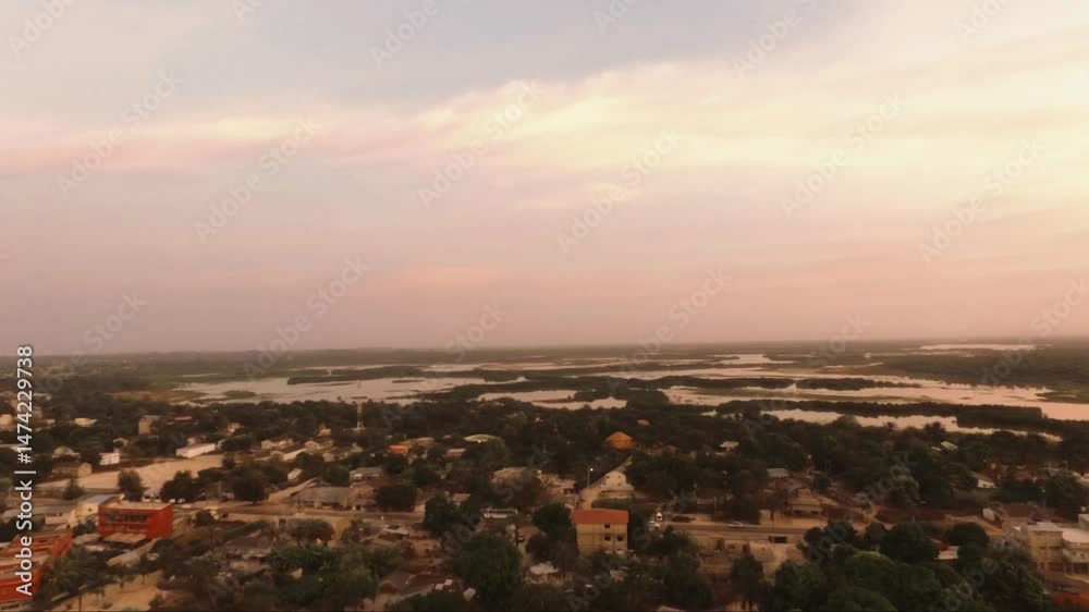 Lever du jour à Cap Skirring depuis les airs, révélant un village paisible niché entre végétation tropicale et bolongs lointains, dans une atmosphère douce et lumineuse typique de Casamance
