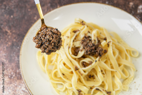 Tagliatelle pasta with chopped black truffle on the spoon