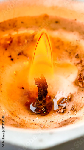 Abstract view of a burning candle with melted wax and flickering flame