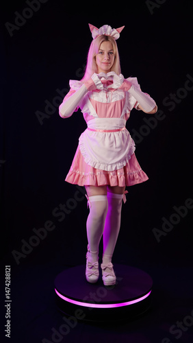 Anime cosplay girl pink maid figurine rotate on platform show love sign with hands on black background