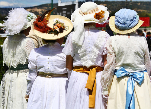 Mujeres vintage vestidas de época clásica belle époque con ropa blanca, sombreros y lazos de colores