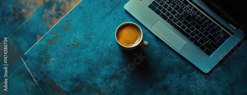 Photo of a blue desk with an open laptop and coffee cup on it, top view for a business concept background banner.
