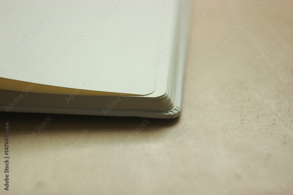 Fototapeta premium Macro view of blank book pages. Close up view of open white pages notebook. Round corners of the sketchbook. Old book on wooden background