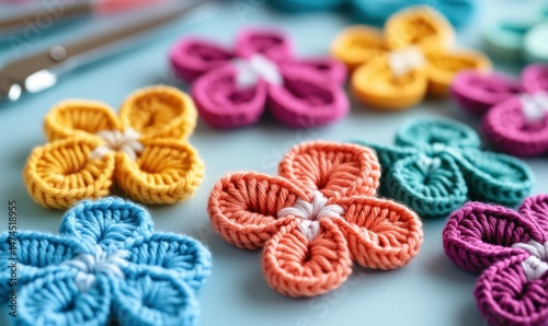 A collection of vibrant, handmade crochet flowers in assorted colors on a blue background.