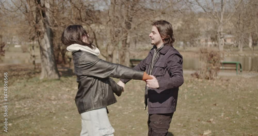 A happy couple enjoys a sunny winter day in the park, laughing and embracing. They spin around, holding hands and hugging, expressing their love and happiness. A happy couple enjoys a sunny winter day in the park, laughing and embracing. They spin around, holding hands and hugging, expressing their love and happiness.