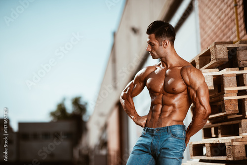 Shirtless muscular young man in jeans standing on the street