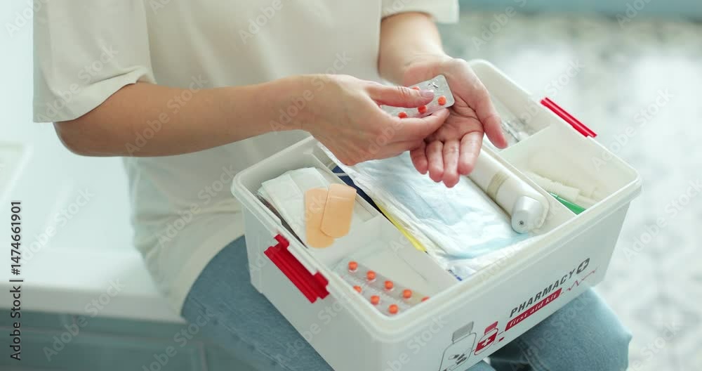 Woman takes out blister of pills from first aid kit at home
