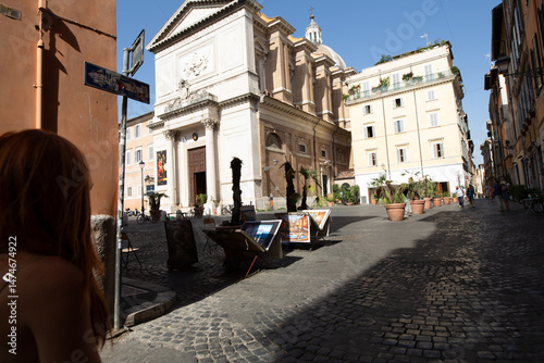 Fototapeta Naklejka Na Ścianę i Meble -  Picturesque Roman square with a church, art displays, and cobblestone streets bathed in sunlight.