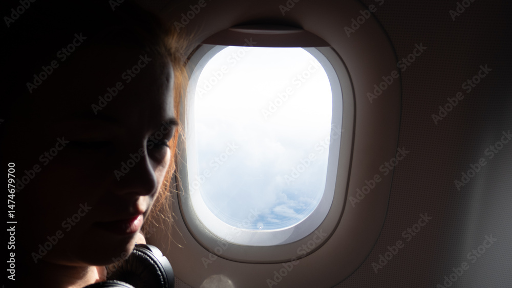 custom made wallpaper toronto digitalSilhouette of a woman looking out an airplane window at clouds and sky.