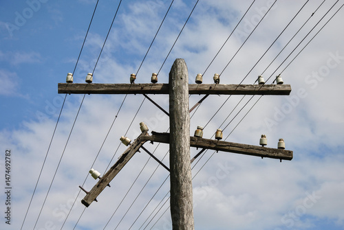 damaged old wooden power line pole against blue sky