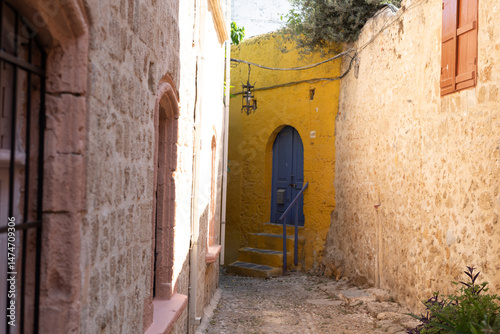 Picturesque alleyway scene.  Historic stone buildings, vibrant yellow wall, blue wooden door, old town charm.