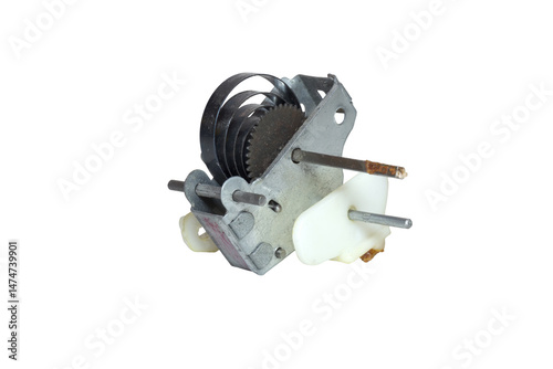 wind-up mechanism of vintage toy. power spring and gear in metal housing, attached plastic element, metal rods, bar for spring tightening. isolated on white background