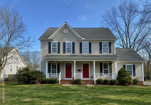 A duplex house with red doors and black shutters on a sunny day in a residential neighborhood view outside
