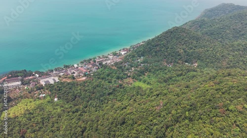 Aerial view capturing turquoise waters lapping sandy coastline of koh chang, revealing verdant tropical forest meeting vibrant village nestled along pristine shoreline
