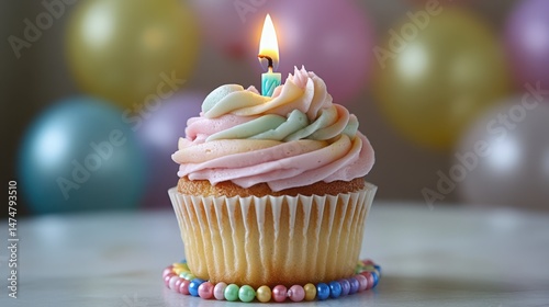 Birthday Dessert Showcase - Festive off-center cupcake featuring pastel frosting, burning candle, rainbow base with beads against balloon bokeh