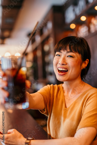 Happy woman toasting with a cold drink in a restaurant