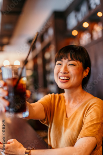 Happy woman toasting with a cold drink at the bar