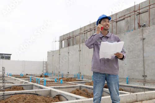 A construction manager in a safety helmet inspects a building site