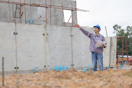 A construction manager in a safety helmet inspects a building site