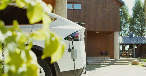 A white electric car charges at a home station in front of a luxury villa, symbolizing clean energy, Eco-friendly transportation, and sustainable living with modern green technology.