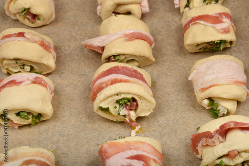 Obraz na płótnie Bacon-wrapped dough rolls filled with a mixture of diced pancetta and herbs are arranged on a baking sheet, ready to be baked w salonie