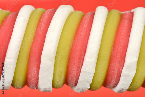 A macro close-up shows the swirled texture of a tri-colored ice cream treat in white, pale green, and pink