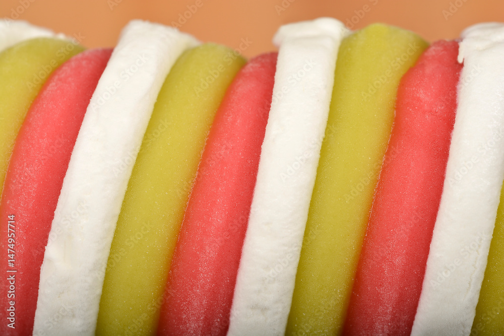 A macro close-up shows the swirled texture of a tri-colored ice cream treat in white, pale green, and pink