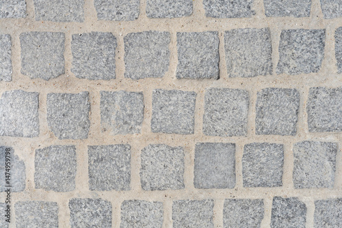 Obraz na płótnie A close-up overhead view shows a section of a cobblestone pavement with square, gray stones and light-colored grout w salonie